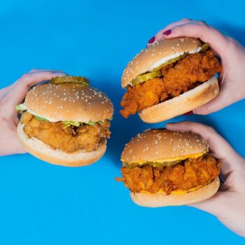 people holding chicken sandwiches